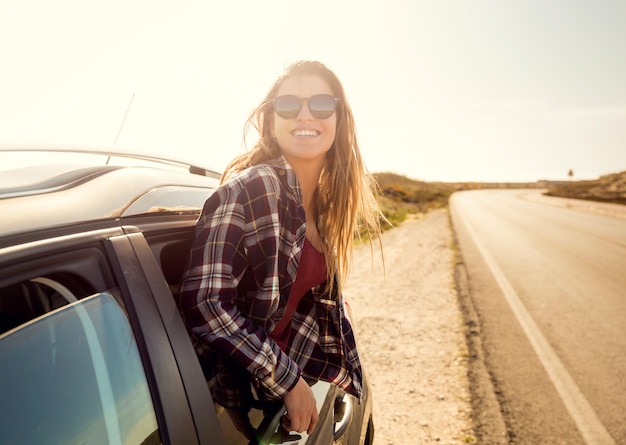 portrait of smiling woman standing by car against sky during winter