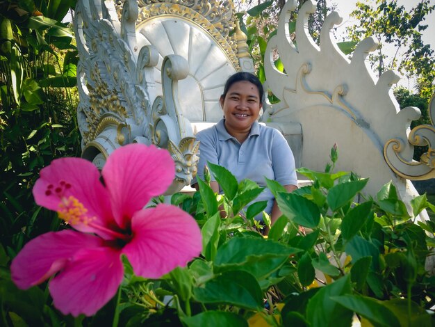 Portrait of smiling woman standing by flowering plants