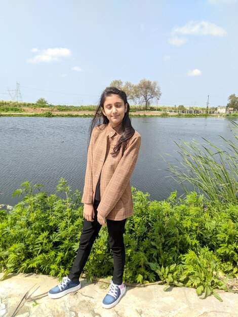 Portrait of smiling woman standing by lake against sky