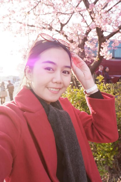 Foto ritratto di una donna sorridente in piedi vicino a fiori rosa