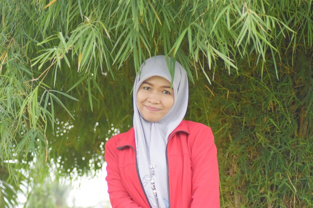 Photo portrait of smiling woman standing by plant leaves