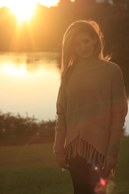 Photo portrait of smiling woman standing on field against lake