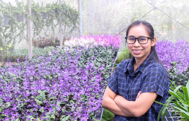 Portrait of smiling woman standing in greenhouse