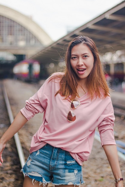 portrait of smiling woman standing at railroad track