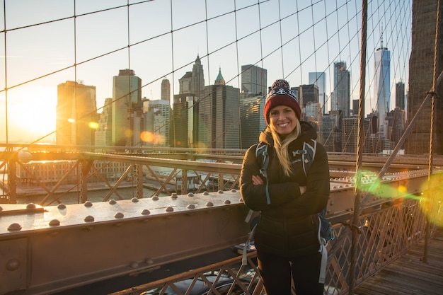 Portrait of smiling woman standing on suspension bridge in city
