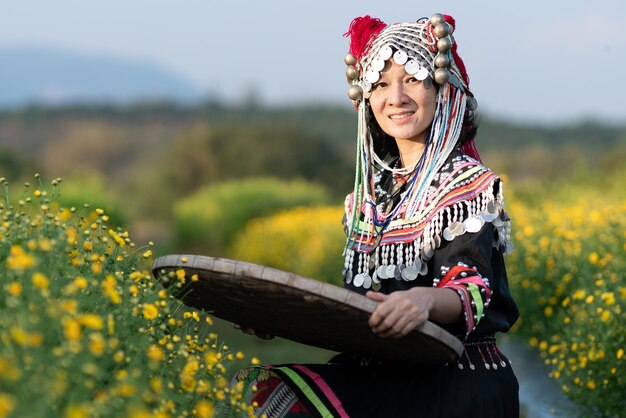 Photo portrait of smiling woman in traditional clothing holding straw basket standing at farm