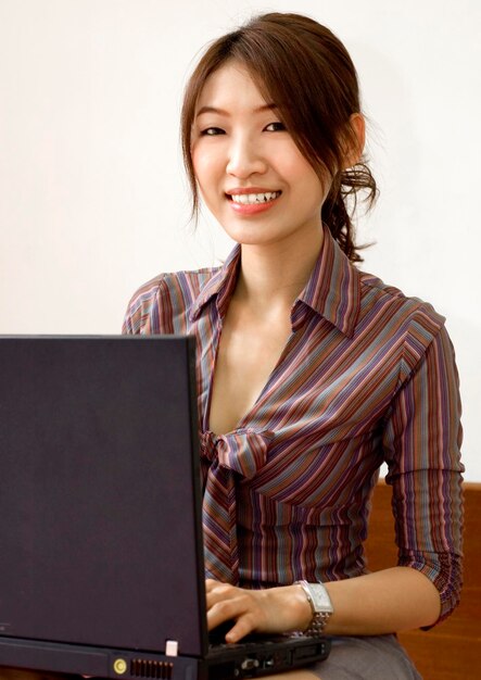 Portrait of smiling woman using laptop against white background