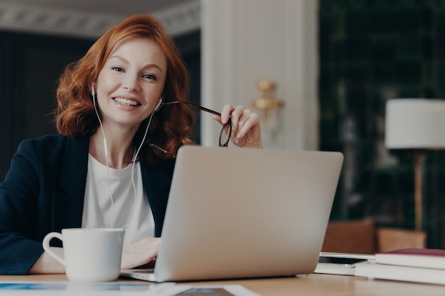 portrait of smiling woman using laptop on desk in office
