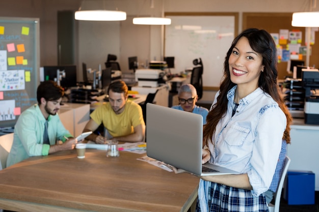 Portrait of smiling woman using laptop at office