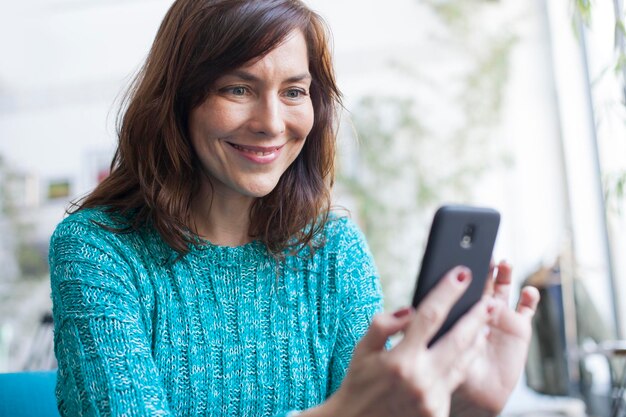 Photo portrait of smiling woman using mobile phone outdoors