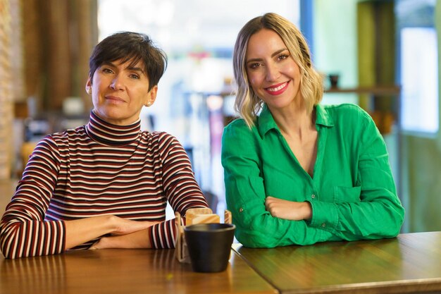 Photo portrait of smiling woman using mobile phone while sitting on table