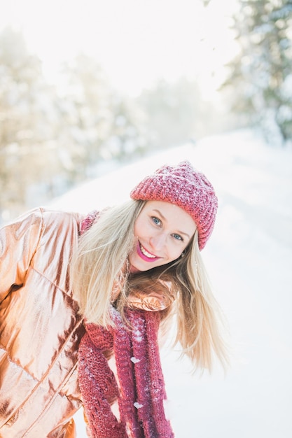 portrait of smiling woman in warm clothing standing on snow