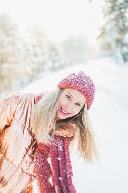 Portrait of smiling woman in warm clothing standing on snow