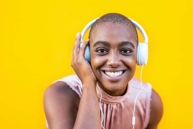 Portrait of smiling woman wearing headphones against yellow background