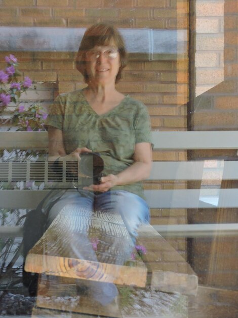 Photo portrait of smiling woman with camera reflecting on glass