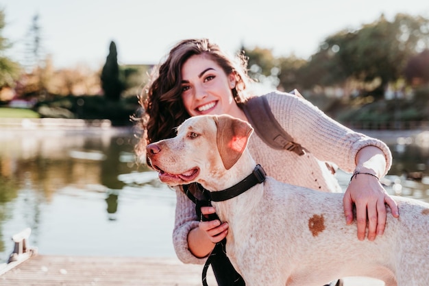 Photo portrait of smiling woman with dog by lake