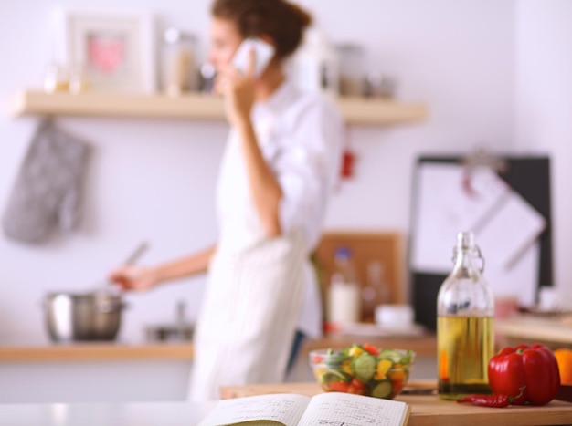 Foto ritratto di una donna sorridente con il telefono in cucina a casa