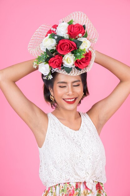 Foto ritratto di una donna sorridente con un fiore rosa sullo sfondo grigio