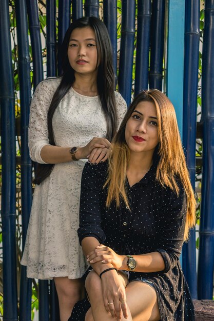 Photo portrait of smiling women standing against bamboo