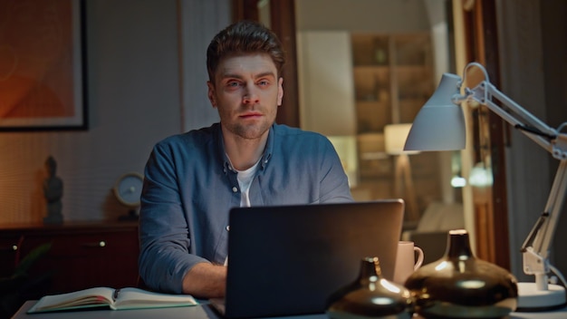 Portrait smiling worker posing at night home table closeup guy working laptop