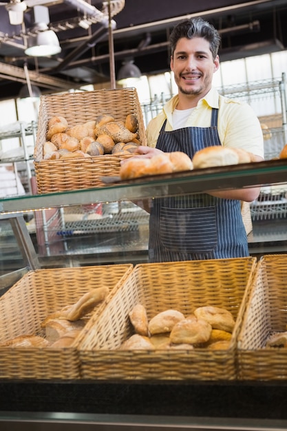 Foto ritratto del lavoratore sorridente che mostra canestro di pane