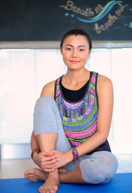 Portrait of smiling yoga woman sitting at yoga mat after workout at yoga studio Yoga Woman