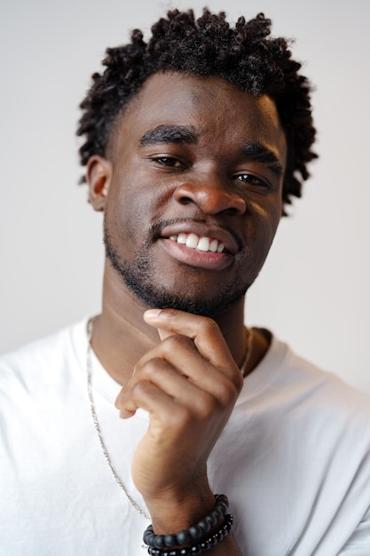 Portrait of a smiling young african man wearing white tshirt standing over gray background