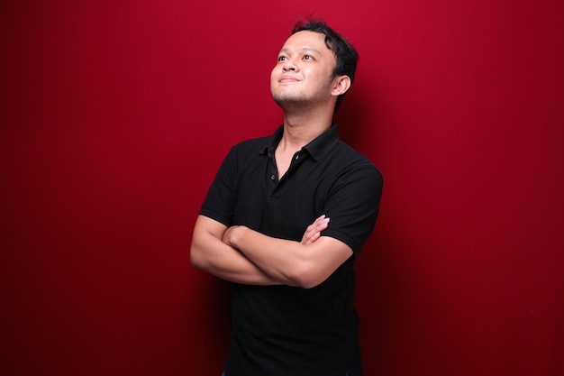 Portrait of smiling young asian man wearing black shirt isolated on red