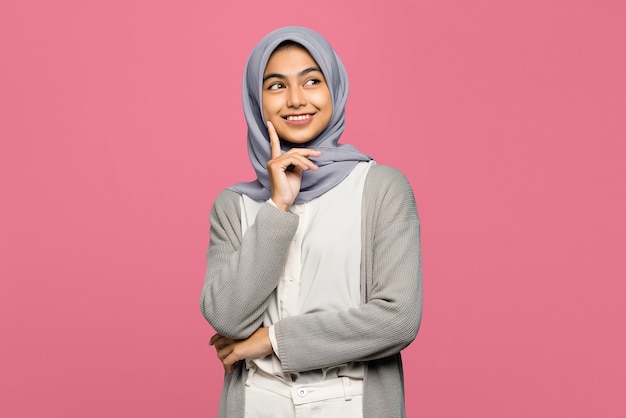 Portrait of smiling young Asian woman looking up and touches her cheek