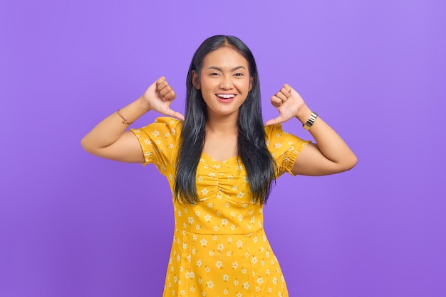 Photo portrait of smiling young asian woman pointing at herself with proud on purple background