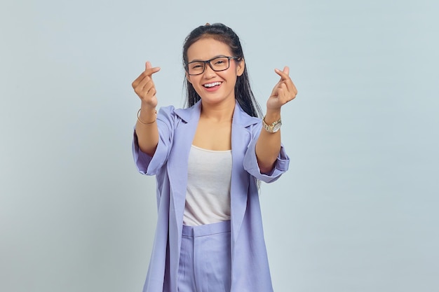 Portrait of smiling young asian woman showing korean heart sign with two fingers crossed, express joy and positivity isolated on white background