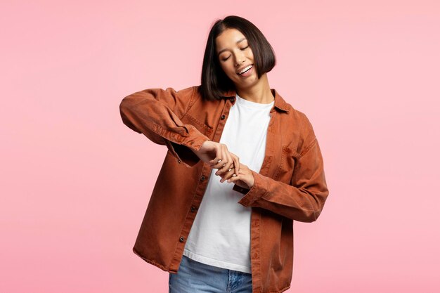 Photo portrait of smiling young asian woman with stylish hairstyle wearing brown casual shirt with closed eyes posing isolated on pink background advertisement concept