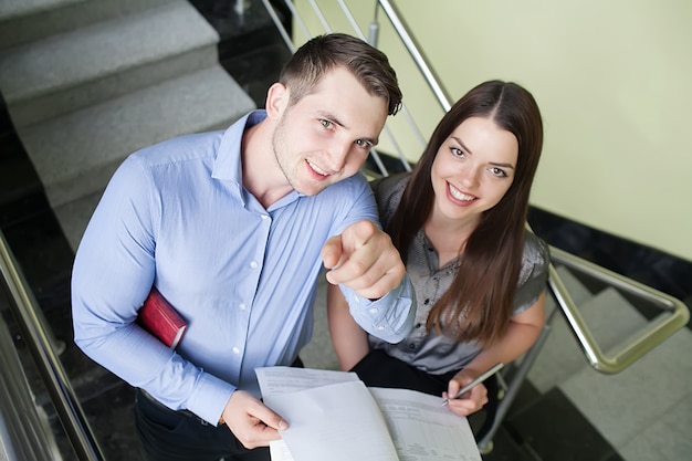 Portrait of a smiling young business couple standing with arms crossed in a office