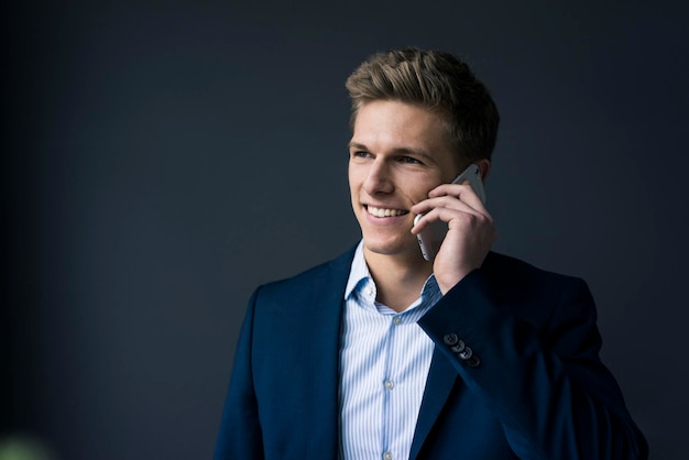 Portrait of smiling young businessman on cell phone