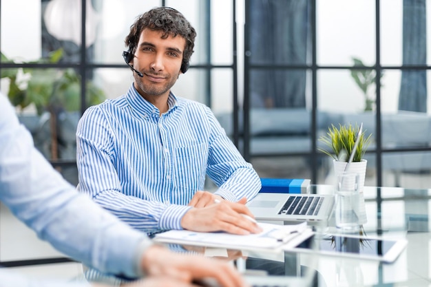 Portrait of a smiling young businessman working on computer at office with his colleague