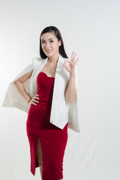 Portrait of smiling young businesswoman gesturing while standing against white background