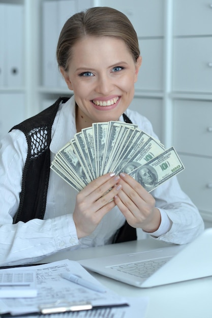 Portrait of smiling young businesswoman holding banknotes