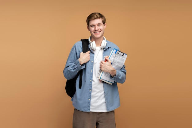 Portrait of smiling young college student with books and backpack