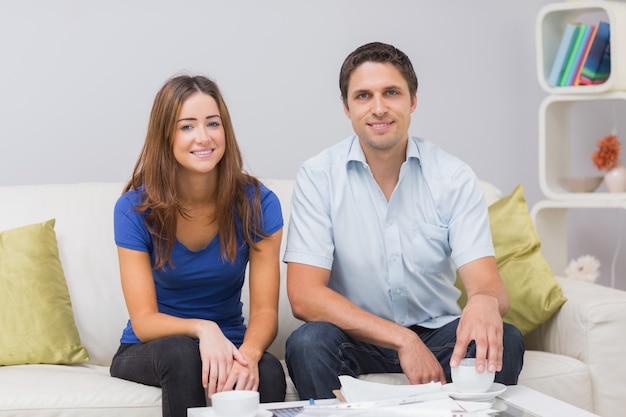 Portrait of a smiling young couple with bills at home