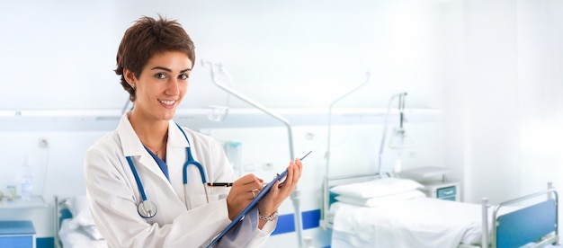 Portrait of a smiling young doctor writing on a clipboard