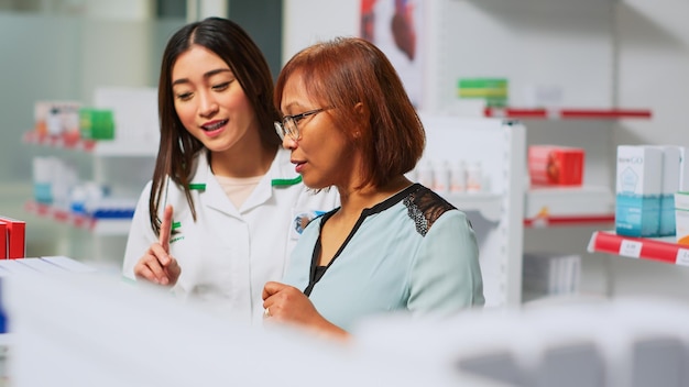 Photo portrait of smiling young female friends using mobile phone in laboratory