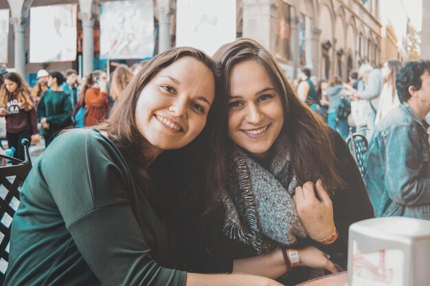 Photo portrait of smiling young friends sitting in city