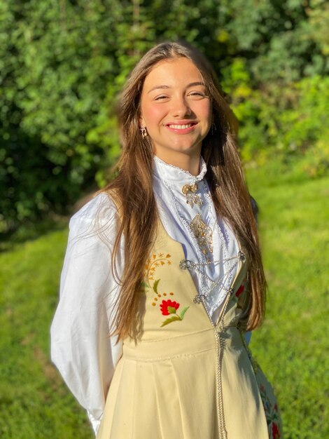 Foto ritratto di una giovane ragazza sorridente che celebra la conferma in bunad