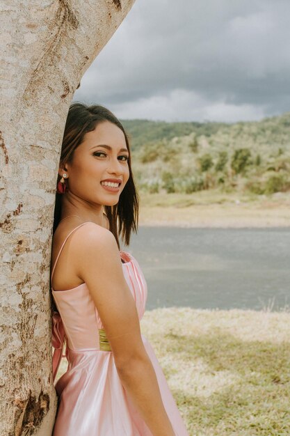 Foto ritratto di una ragazza sorridente in piedi vicino a un albero