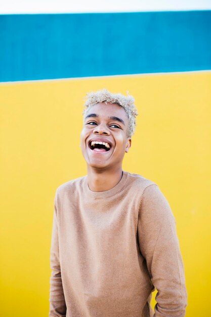 Foto ritratto di un giovane maschio latinoamericano sorridente su uno sfondo blu e giallo