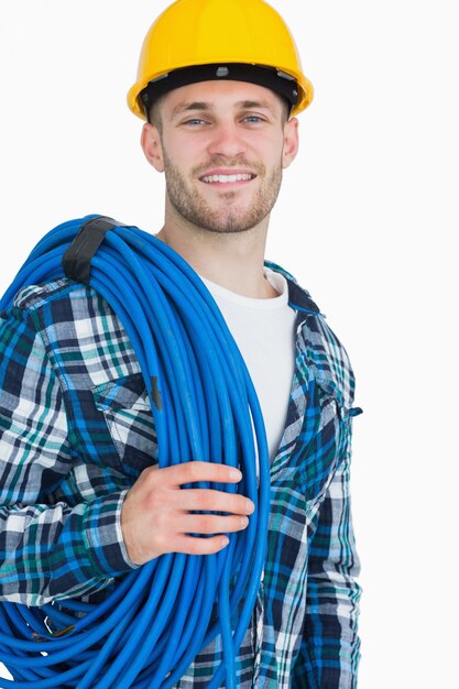 Portrait of smiling young male architect carrying coiled blue tubing