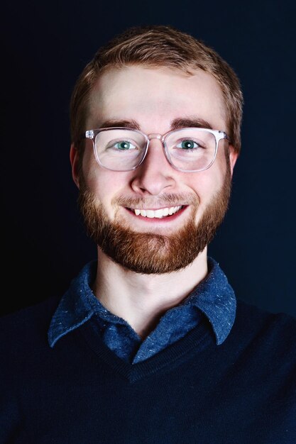 portrait of smiling young man against black background