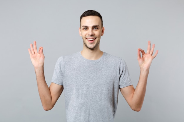 Portrait of smiling young man in casual clothes holding hands in yoga gesture relaxing meditating 