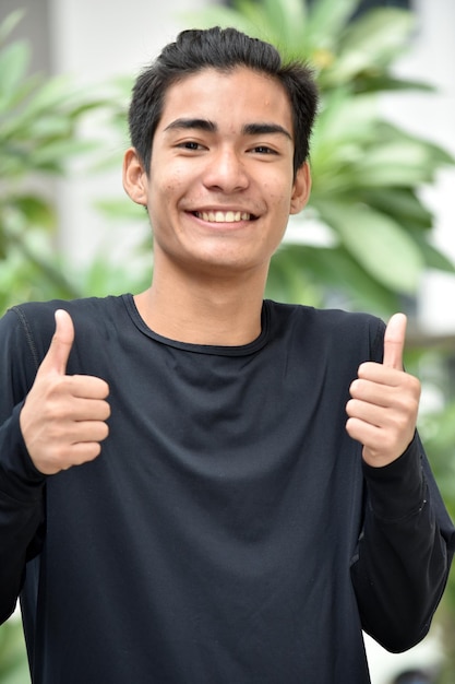 Portrait of smiling young man gesturing while standing against plants