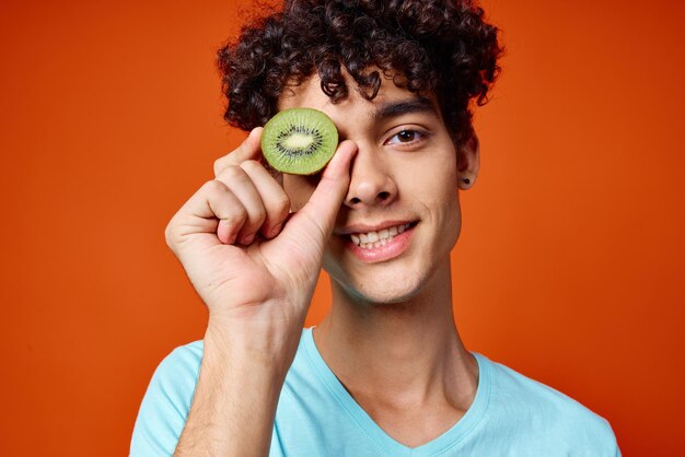 Portrait of smiling young man holding apple against orange background